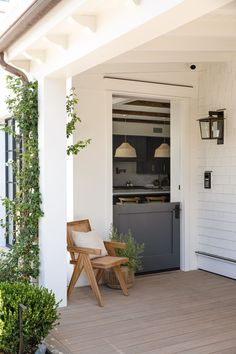 a wooden chair sitting on top of a porch next to a white wall and door