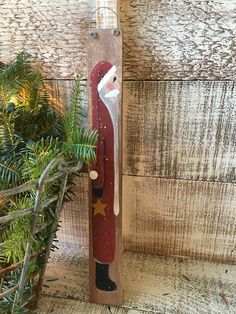 a wooden christmas decoration with a santa clause on it's face and tree branches in the background