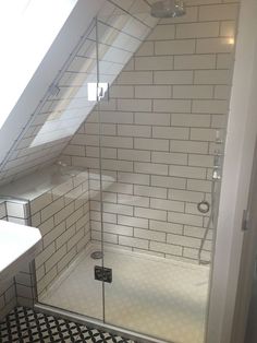 a bathroom with a black and white tile floor, shower stall and skylight in the corner