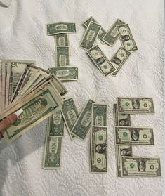 a person holding money in their hand with the word love spelled out over them on a bed sheet