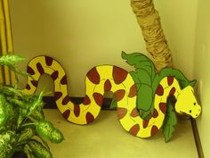 a wooden sign with a snake painted on it's side next to a potted plant