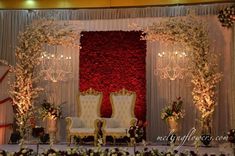 a decorated stage with two chairs and flowers