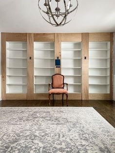 a chair sitting on top of a rug in front of a book shelf filled with books