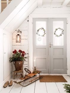 a white door with two wreaths on it and some flowers in the window sill