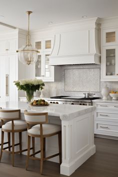 a kitchen with white cabinets and an island in the middle, surrounded by bar stools