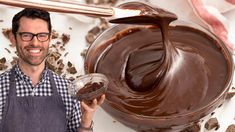 a man in an apron is holding a jar of chocolate and smiling at the camera