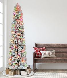 a brightly colored christmas tree next to a wooden bench in a room with white walls