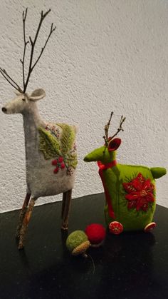 two stuffed animals sitting next to each other on top of a black table with white wall in the background