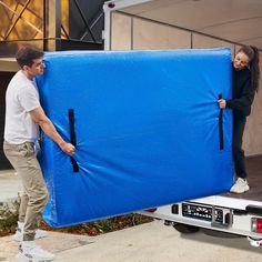 a man and woman unloading a large blue sheet