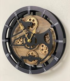 a clock made out of wood and metal with gears attached to the face, on a white wall