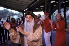 a group of people standing around each other in front of a man with a long white beard