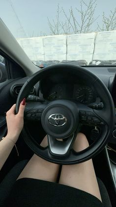 a woman is sitting in the driver's seat of a car with her hands on the steering wheel