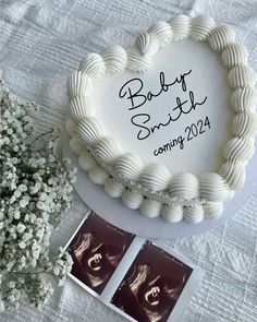 a white cake sitting on top of a table next to some flowers and an album