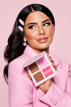 a woman holding up a pink box with her face painted in the same shade as she is