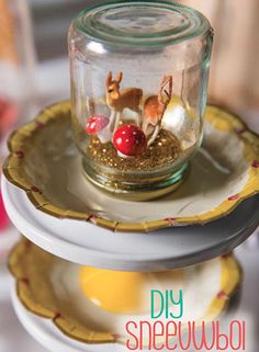 there is a small glass jar with tiny animals in it on top of two plates