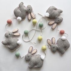 several felt bunny ornaments are arranged on a white surface with string lights attached to them