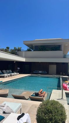 people lounging on lounge chairs in front of a swimming pool