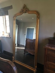 a large gold framed mirror sitting on top of a wooden dresser