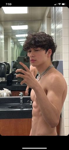 a shirtless young man standing in front of a bathroom mirror holding his hand out