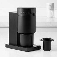 a coffee maker sitting on top of a counter next to a cup