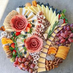 an assortment of cheeses and fruits arranged in the shape of a heart