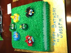 a birthday cake decorated with angry birds on top of green grass and yellow frosting