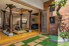 the inside of a house with wooden pillars and green grass on the ground, surrounded by brick walls