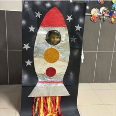 a cardboard rocket ship with a child's face in the center and stars on it