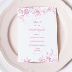 a white plate topped with a menu and pink flowered design on top of it