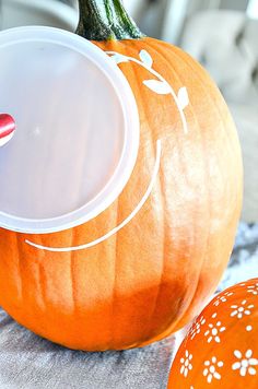 an orange pumpkin sitting on top of a table next to two white bowls with designs painted on them