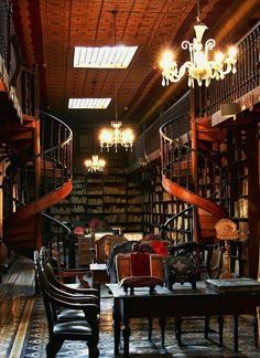 an old library with many bookshelves and chandeliers