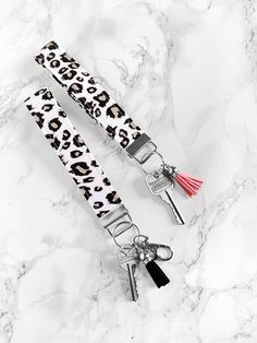 two keychains with leopard print and tassels on top of marble surface