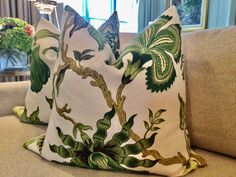 two green and white pillows sitting on top of a couch next to a vase with flowers