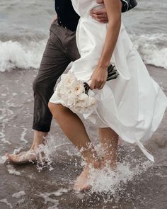 a bride and groom are walking through the water on their wedding day at the beach