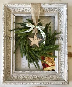 a christmas wreath hanging from the side of a white frame with a star and ribbon on it