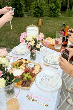 people are sitting at a table with plates and flowers in vases, taking pictures