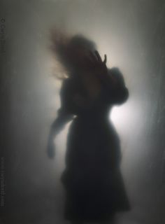 a blurry image of a woman in a long dress with her hair blowing in the wind