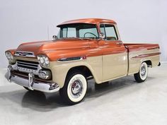 an old truck is parked in a room with white walls and gray flooring,