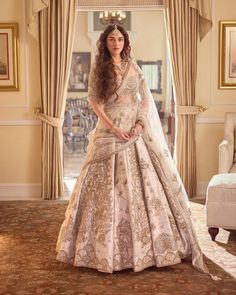 a woman in a white and gold bridal gown posing for the camera with her hand on her hip