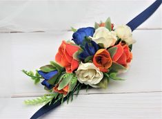 a bridal bouquet with orange, white and blue flowers on a wooden table top