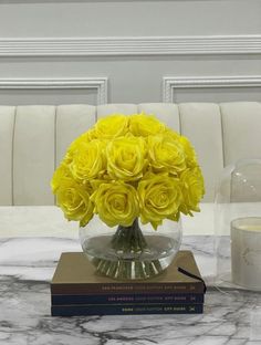 a vase filled with yellow roses sitting on top of a table next to a book