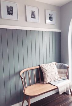 a wooden bench sitting on top of a hard wood floor next to a wall with pictures above it