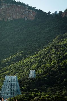 two blue buildings are on the side of a mountain with trees in front of them