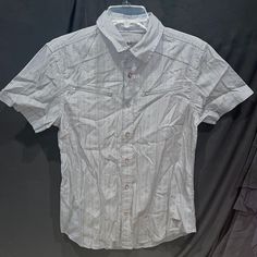 Go From Work To Weekend In This Short-Sleeve Shirt Featuring A Woven Subtle Striped Design, Folded Collar And Dual Zipper Chest Pockets. Front Button Closures. Signature Triangle On Bottom Front Corner. Color: Gray 100% Cotton Machine Wash Armpit To Armpit 18.5 Inches Shoulder To Shoulder: 16.5” Around Arm: 13” Top Shoulder To Bottom Hem 27 Inches Casual Short Sleeve Blouse With Button Closure, White Short Sleeve Tops With Buttons, Fitted Collared Shirt, Casual Style, Fitted Casual Collared Shirt, Casual Fitted Collared Shirt, White Short Sleeve Blouse With Button Closure, White Blouse With Button Closure And Short Sleeves, Fitted Casual Tops With Placket, White Short Sleeve Blouse With Placket