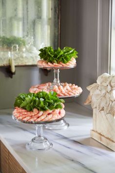 three tiered trays with shrimp and lettuce on them sitting on a marble counter