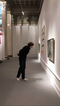 a man standing in an empty room looking at pictures on the wall and ceiling,