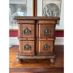 an old wooden dresser sitting on top of a hard wood floor next to framed pictures