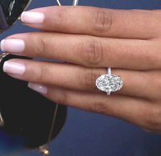 a woman's hand with a diamond ring on her finger and sunglasses in the background