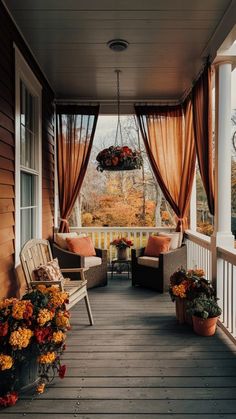 a porch with chairs and flowers on the front steps, covered in orange drapes