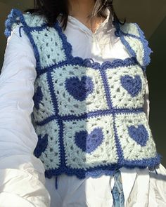 a close up of a person wearing a crocheted vest with hearts on it